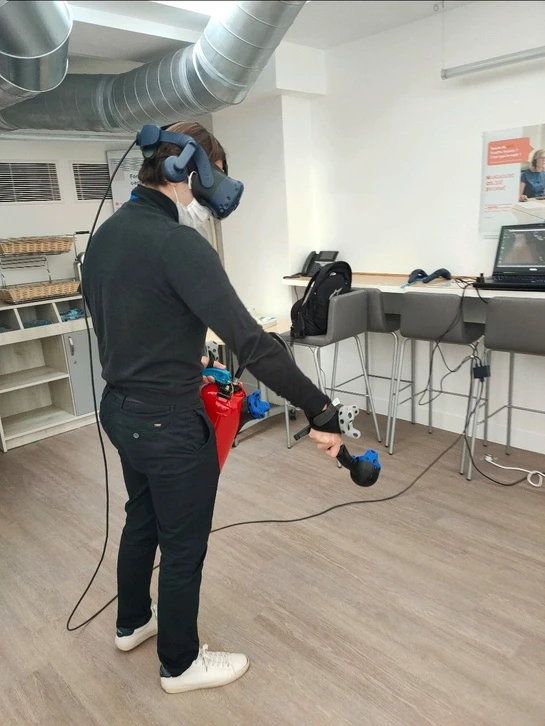 Deux extincteurs rouges portables posés sur moquette beige, équipés de supports imprimés en 3D en PLA noir montant des trackers HTC Vive